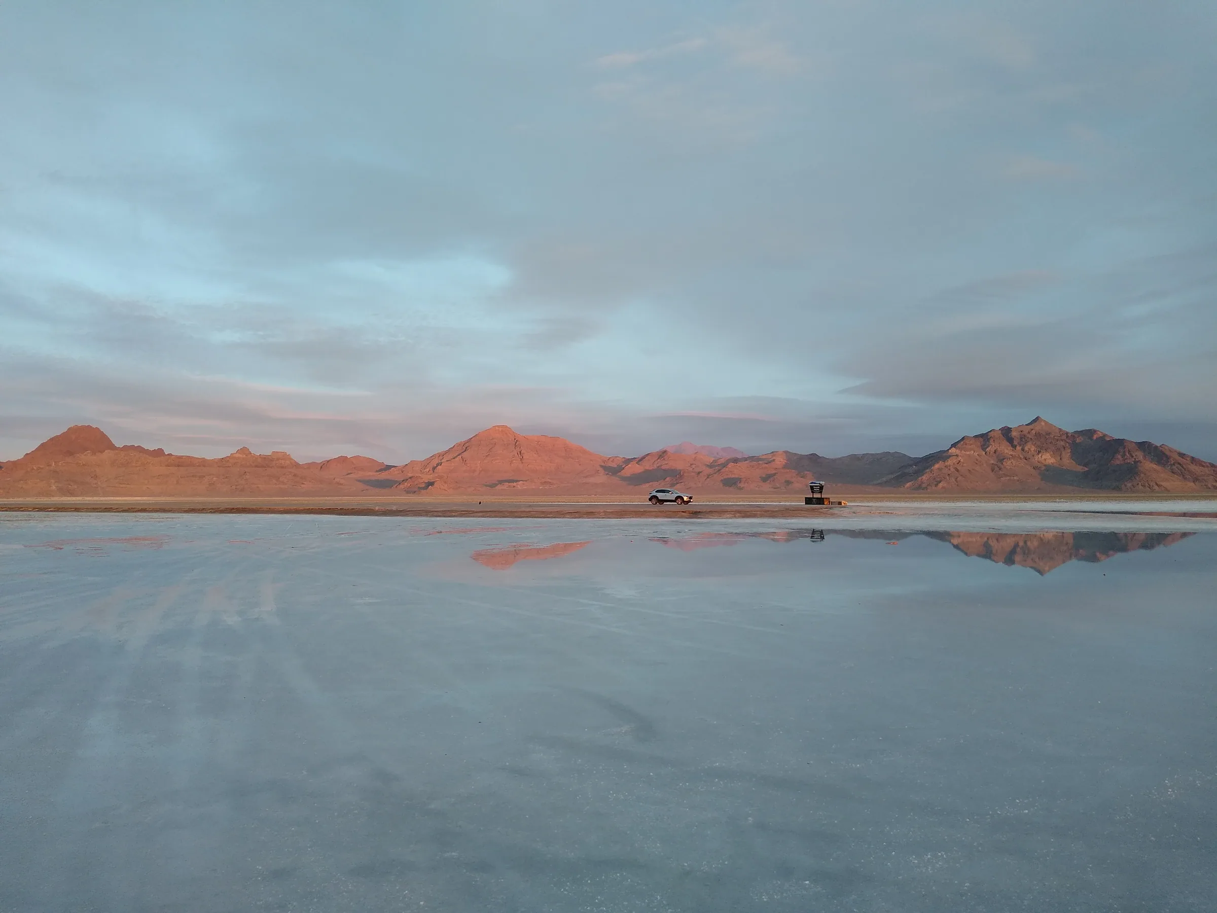 Sunrise reflected in the shallow water covering the Bonneville Salt Flats, the mountains doubled in the mirror.